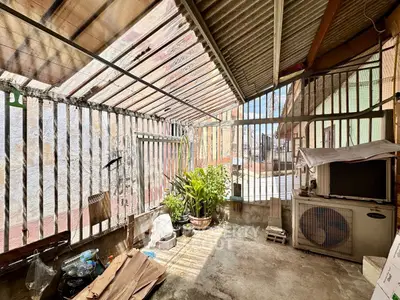 Spacious outdoor area with corrugated roof and potted plants, ideal for urban gardening.