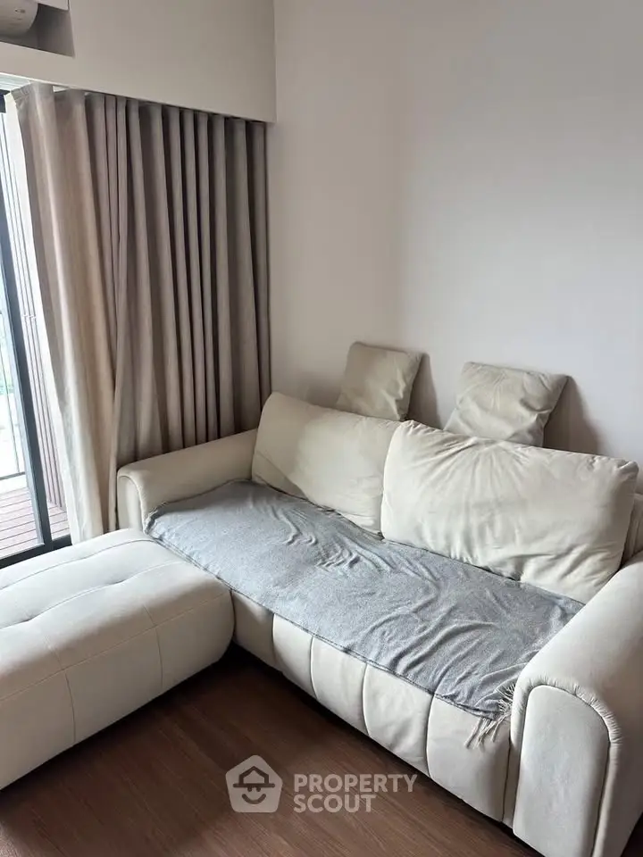 Cozy living room with plush white sofa and elegant curtains, perfect for relaxation.
