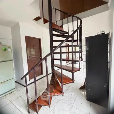 Spiral staircase in modern home interior with tiled flooring and wooden accents.