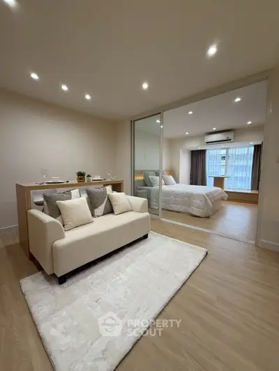 Modern open-plan living room with cozy sofa and elegant bedroom view