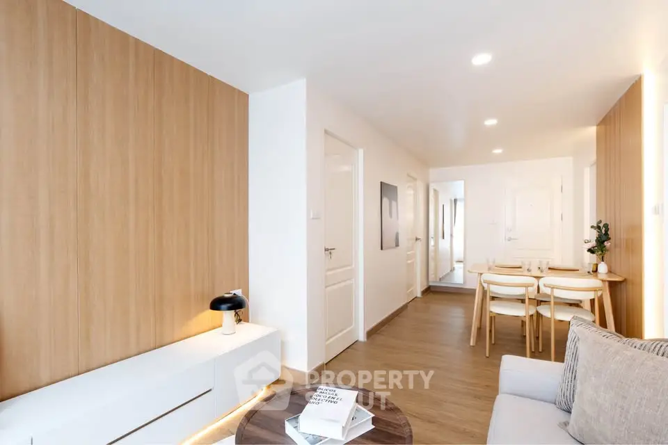 Modern living room with wooden accents and cozy dining area in open layout apartment.