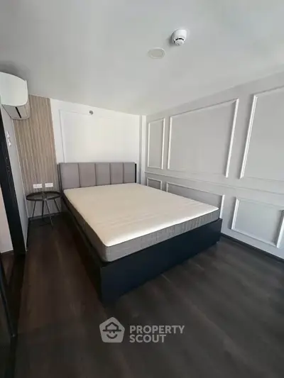 Spacious modern bedroom with elegant paneling and dark wood flooring