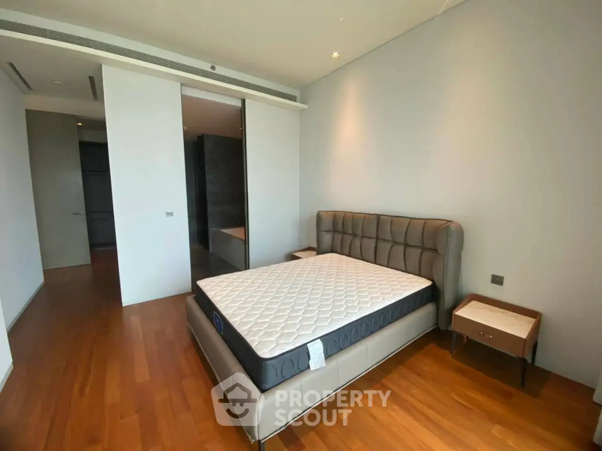 Spacious bedroom with modern design and wooden flooring in luxury apartment.