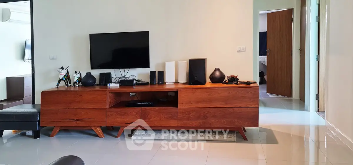 Modern living room with sleek wooden furniture and flat-screen TV, showcasing contemporary interior design.