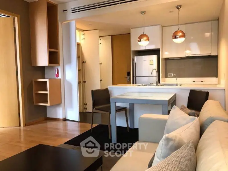 Modern open-layout kitchen and living area with stylish lighting and cozy seating.