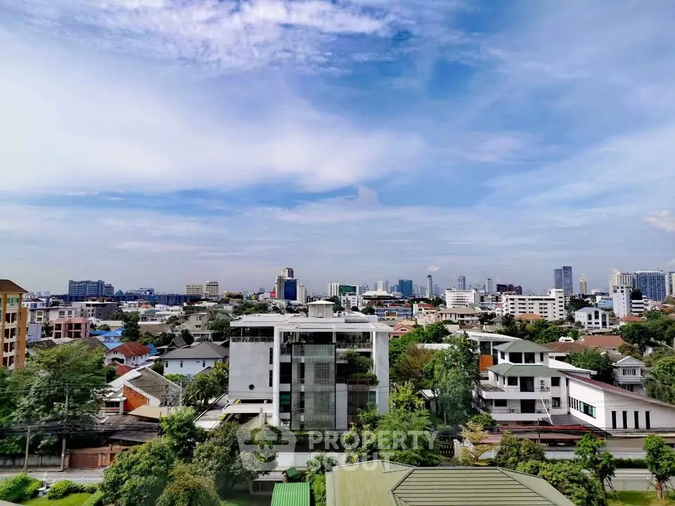Stunning cityscape view with modern buildings and lush greenery under a clear blue sky.