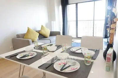 Modern dining area with elegant table setting and cozy living room in bright apartment.