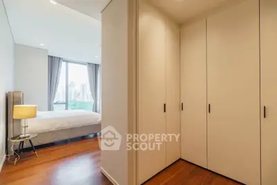 Spacious bedroom with elegant wooden flooring and large windows offering a stunning city view.