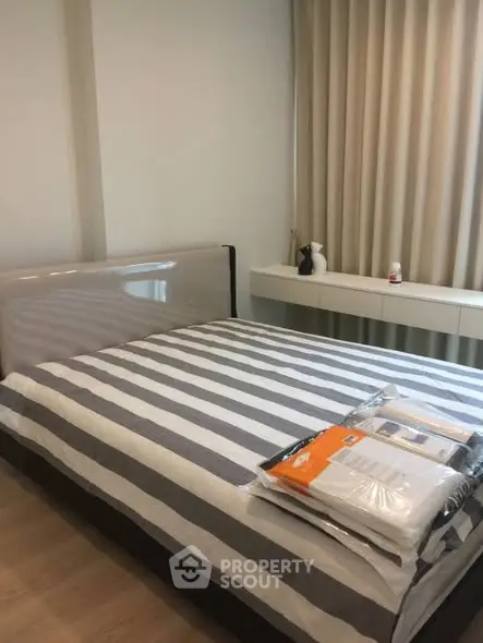 Cozy bedroom with striped bedding and modern decor, perfect for relaxation.