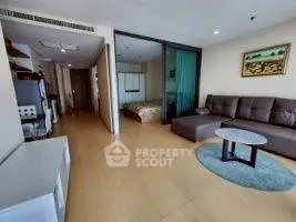 Spacious living room with modern decor and adjacent bedroom in open layout apartment.