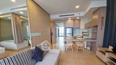 Modern open-plan living room with kitchen and dining area, featuring wooden flooring and stylish decor.