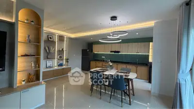 Modern open-layout kitchen and dining area with stylish lighting and sleek cabinetry.