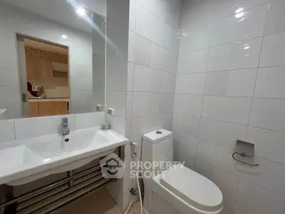 Modern bathroom with sleek white tiles and contemporary fixtures in a stylish apartment.