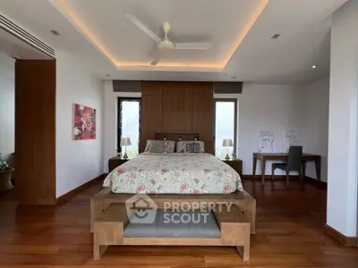 Spacious bedroom with elegant wooden flooring and modern decor, featuring a comfortable bed and stylish furniture.