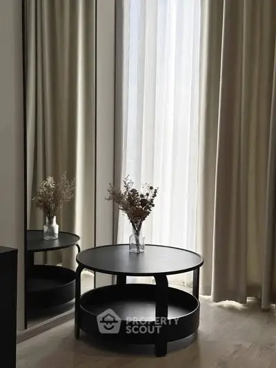 Elegant modern interior with round table and decorative vase by large window.