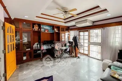 Spacious living room with ceiling fan and ample natural light, featuring stylish wooden cabinetry.