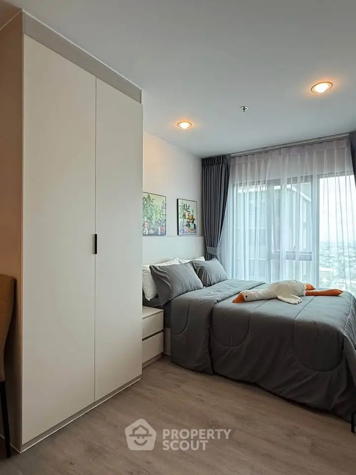 Modern bedroom with stylish decor and large window offering natural light.