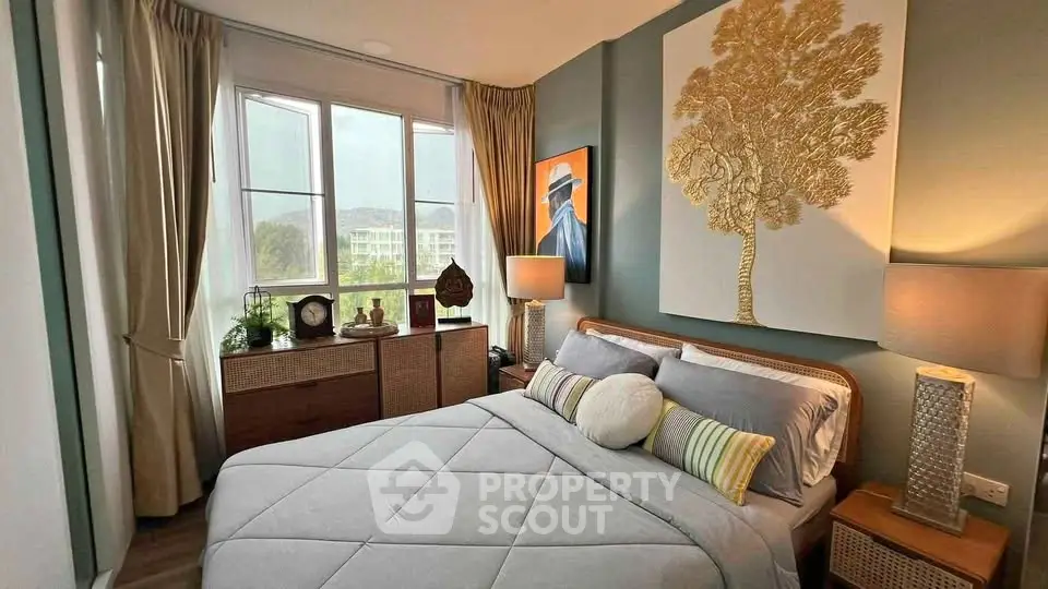 Cozy bedroom with stylish decor and large window offering natural light and scenic views.