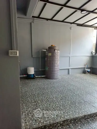 Spacious utility area with water tank and tiled flooring, ideal for storage or laundry setup.