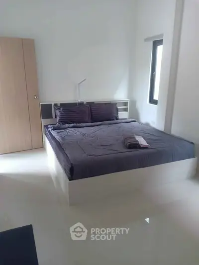 Modern bedroom with sleek design and natural light, featuring a comfortable bed and minimalist decor.