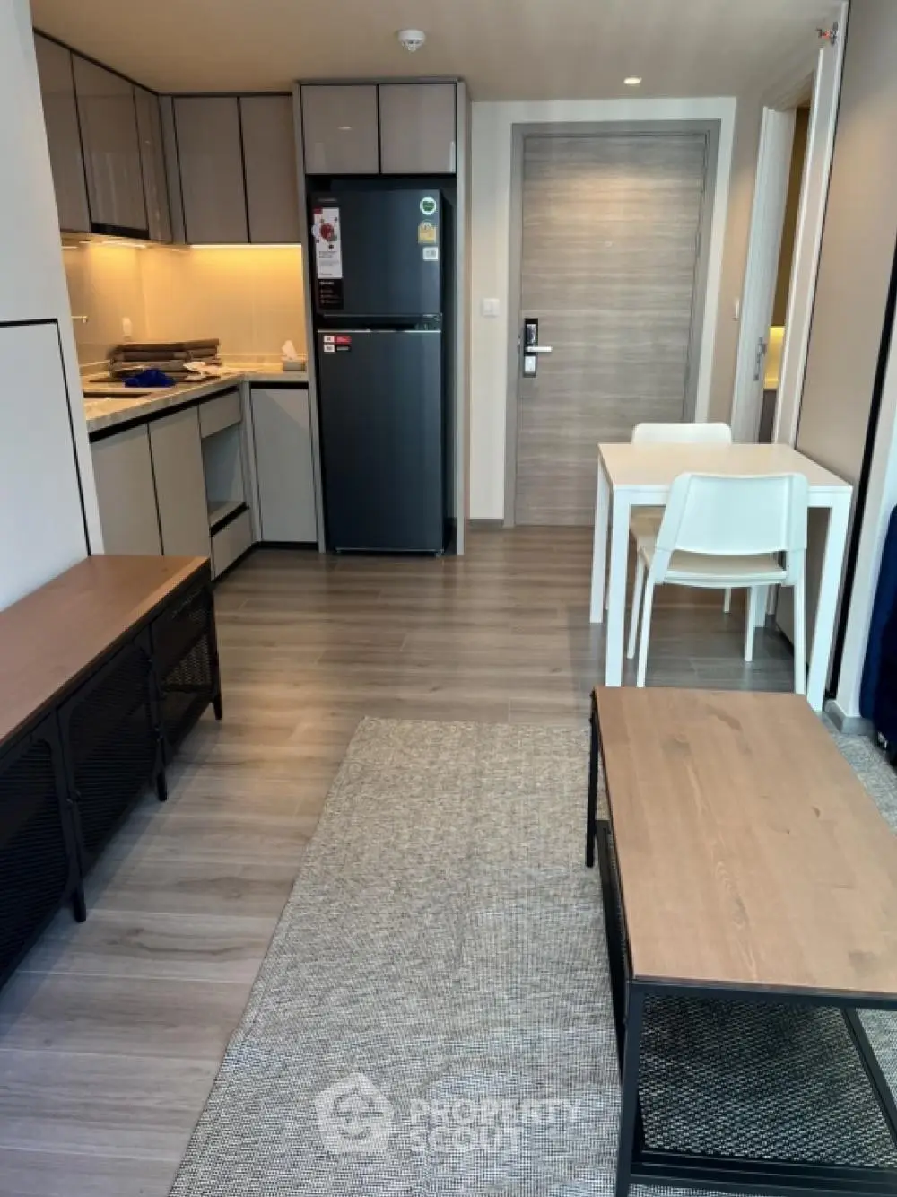 Modern apartment interior with compact kitchen and dining area, featuring sleek design and contemporary furniture.