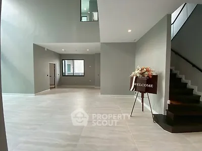 Spacious modern living room with elegant staircase and welcome sign