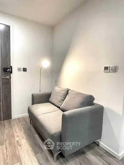 Cozy modern living room with stylish gray sofa and sleek wooden flooring.
