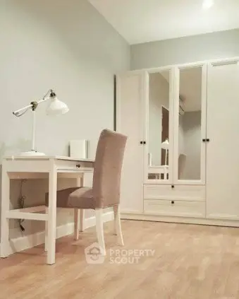 Elegant study room with white desk, chair, and mirrored wardrobe in modern apartment.