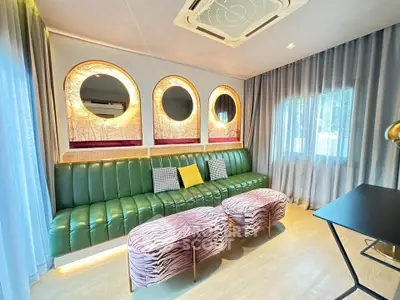 Stylish living room with green leather sofa, zebra-patterned ottomans, and elegant lighting.