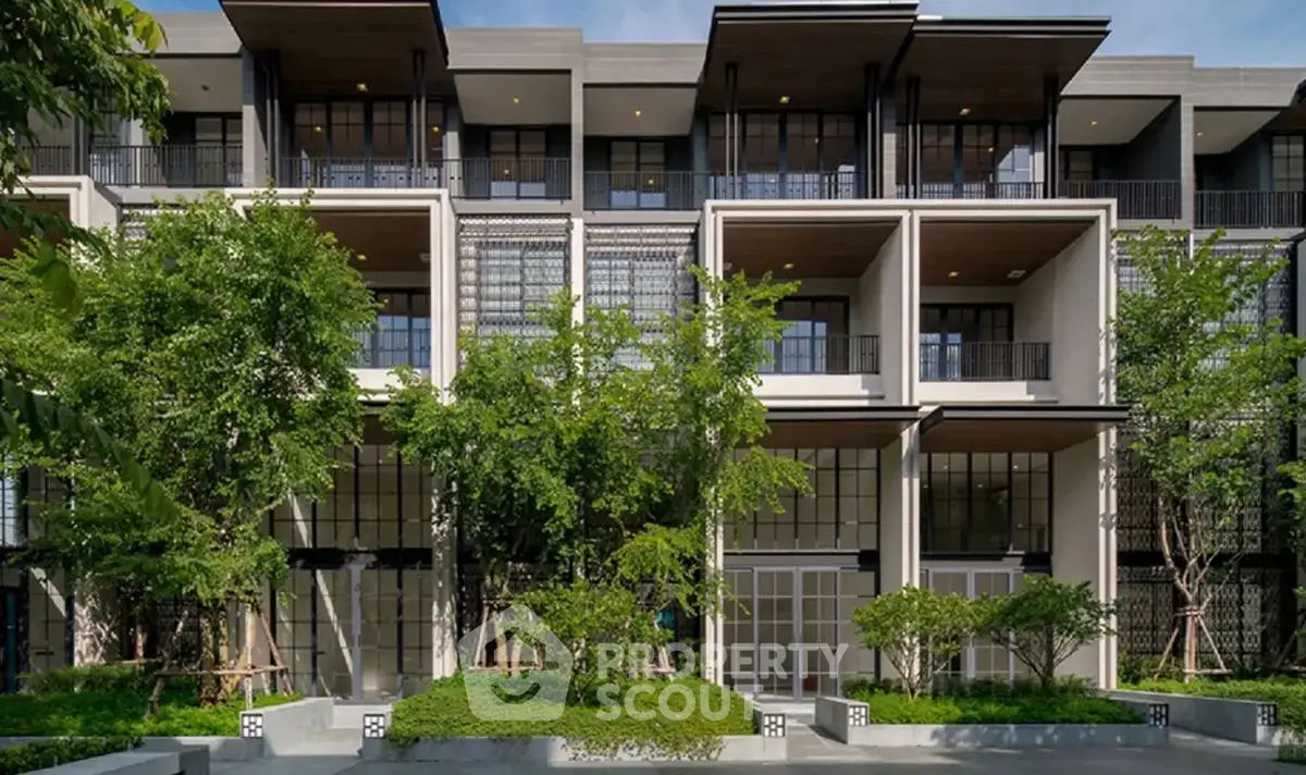 Modern multi-story building with lush greenery and large windows