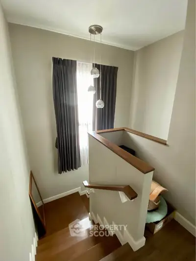 Charming staircase with elegant pendant lighting and wooden handrails in a cozy home setting.