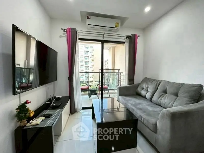 Modern living room with balcony view, featuring sleek furniture and a wall-mounted TV.