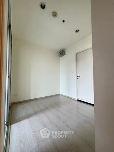 Spacious empty room with wooden flooring and white walls, ideal for customization.
