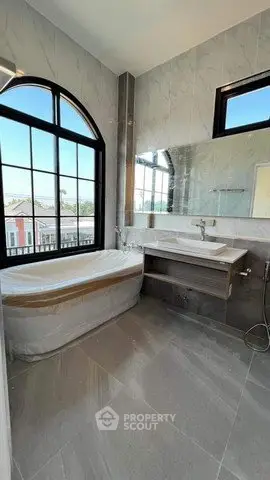 Luxurious bathroom with elegant bathtub and large window offering natural light and scenic views.