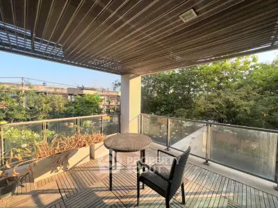 Spacious balcony with modern design and lush greenery view, perfect for relaxation.