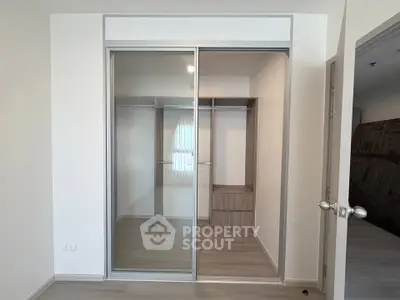 Spacious bedroom with modern sliding door closet and elegant wooden flooring.