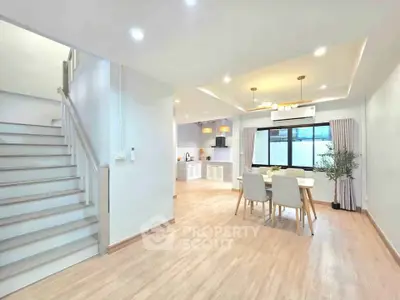 Spacious open-plan living and dining area with modern kitchen and elegant staircase.