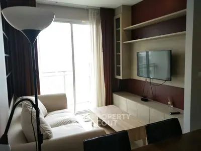 Modern living room with cozy sofa, wall-mounted TV, and natural light from balcony.