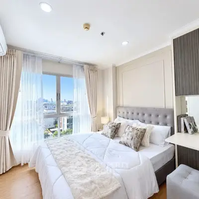 Luxurious bedroom with city view, elegant decor, and ample natural light.