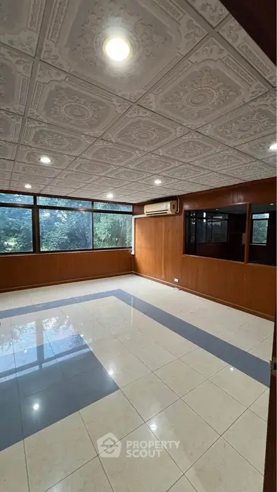 Spacious room with elegant ceiling tiles and large windows overlooking greenery