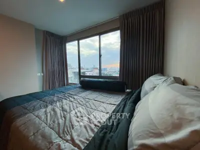 Spacious bedroom with large window offering stunning city view and elegant curtains.