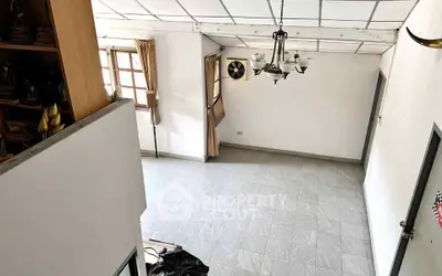 Spacious living room with tiled flooring and elegant chandelier in a bright, airy home.