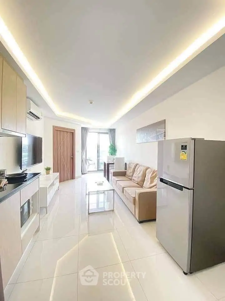 Modern living room with sleek design, featuring a comfortable sofa and stainless steel fridge.