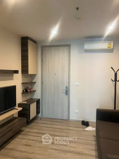 Modern living room with sleek design, featuring wooden flooring, wall-mounted TV, and air conditioning.