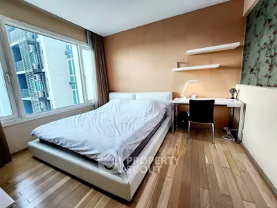 Modern bedroom with wooden flooring, large window, and study desk