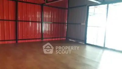 Spacious industrial-style room with metal walls and wooden flooring, ideal for creative workspace.