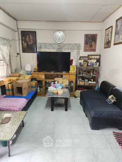 Cozy living room with TV, sofa, and decorative shelves in a homely setting.
