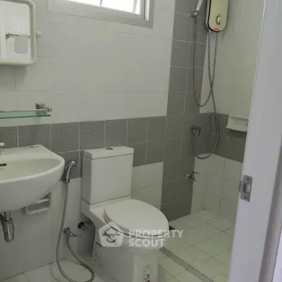 Modern bathroom with shower, toilet, and sink in a sleek tiled design.