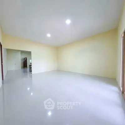 Spacious empty room with glossy tile flooring and soft yellow walls, ideal for customization.