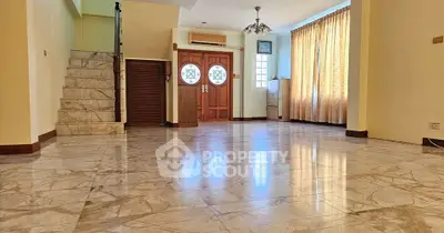 Spacious living room with marble flooring and elegant wooden door